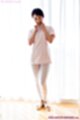 Standing beside curtained window wearing white short hair bare feet