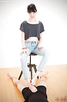 Sitting on stool wearing grey top in jeans teasing cock with bare feet