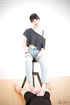 Seated on stool in jeans giving barefoot footjob
