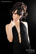 Forefinger extended to lips in black dress wearing hair up